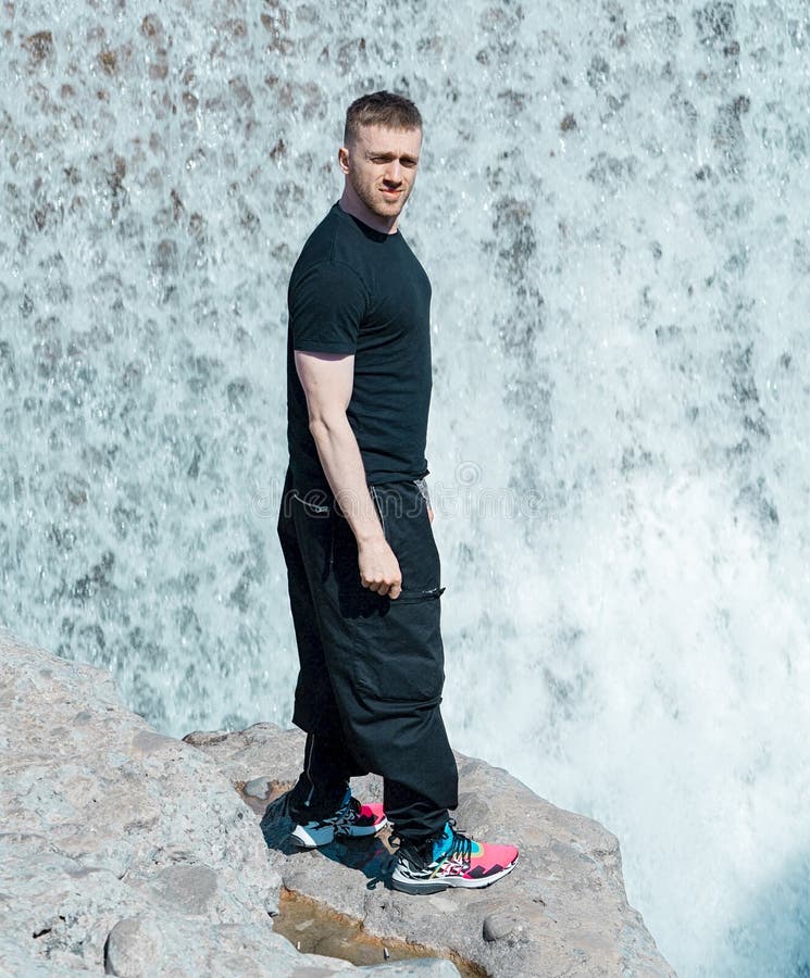 Przystojna mężczyzna pozycja obok siklawy Blogger i podróżnik na wakacje fotografia royalty free Przystojna mężczyzna pozycja obok siklawy Blogger i podróżnik na wakacje fotografia royalty free