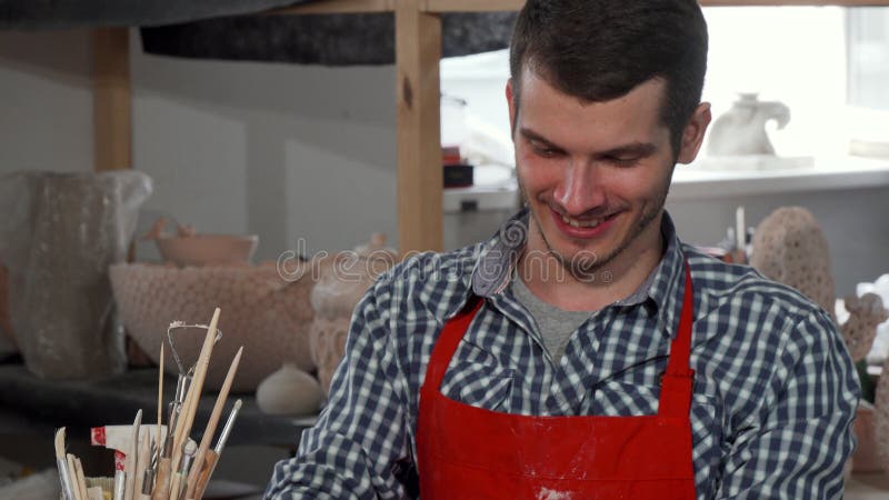 Przystojna rozochocona męska garncarka cieszy się pracować przy jego studiiem obraz stock Przystojna rozochocona męska garncarka cieszy się pracować przy jego studiiem obraz stock