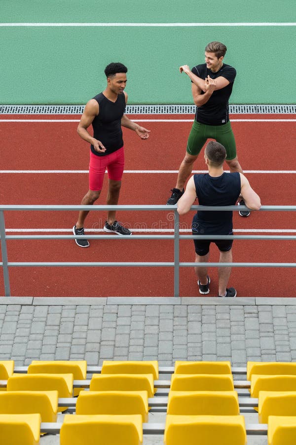 Przystojna wieloetniczna atlety grupa robi rozciągań ćwiczeniom obraz stock Przystojna wieloetniczna atlety grupa robi rozciągań ćwiczeniom obraz stock