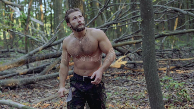 Przystojny brodaty mężczyzna chodzi z ax w lesie 4K
