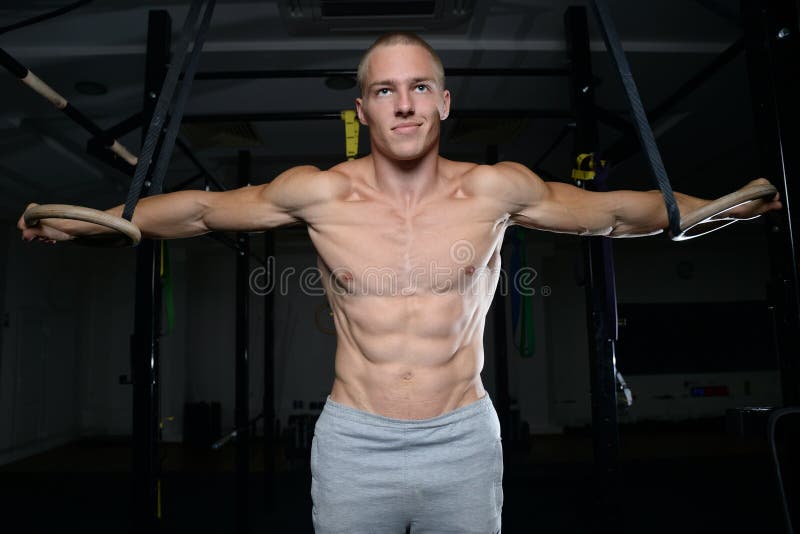 Przystojny mężczyzna atlety szkolenie przy gimnastycznymi pierścionkami obraz stock Przystojny mężczyzna atlety szkolenie przy gimnastycznymi pierścionkami obraz stock