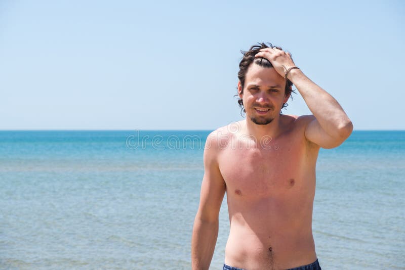 Przystojny mężczyzna pozuje na plaży, portret Ręka w włosy obraz stock Przystojny mężczyzna pozuje na plaży, portret Ręka w włosy obraz stock