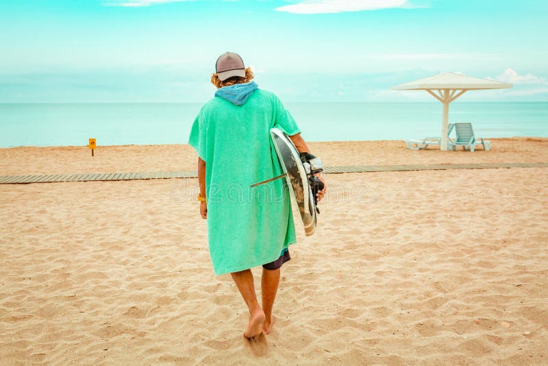 Przystojny mężczyzna spacer z białą pustą surfing deską czekać na fala surfować punkt przy dennym oceanu brzeg widok z powrotem P fotografia stock Przystojny mężczyzna spacer z białą pustą surfing deską czekać na fala surfować punkt przy dennym oceanu brzeg widok z powrotem P fotografia stock