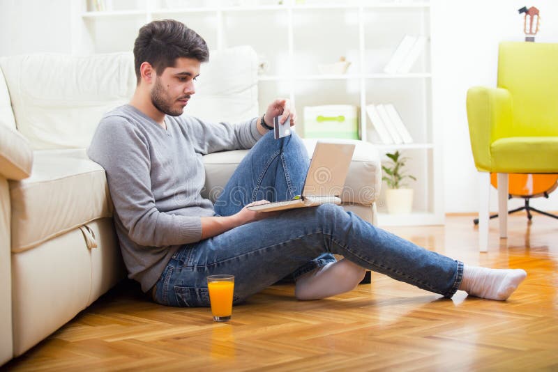 Przystojny mężczyzna trzyma kredytową kartę i używa laptop dla online zakupy fotografia stock Przystojny mężczyzna trzyma kredytową kartę i używa laptop dla online zakupy fotografia stock