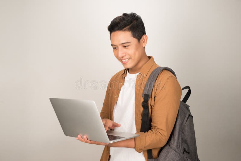 Przystojny młody student używający laptopa z plecakiem na białym tle fotografia royalty free Przystojny młody student używający laptopa z plecakiem na białym tle fotografia royalty free