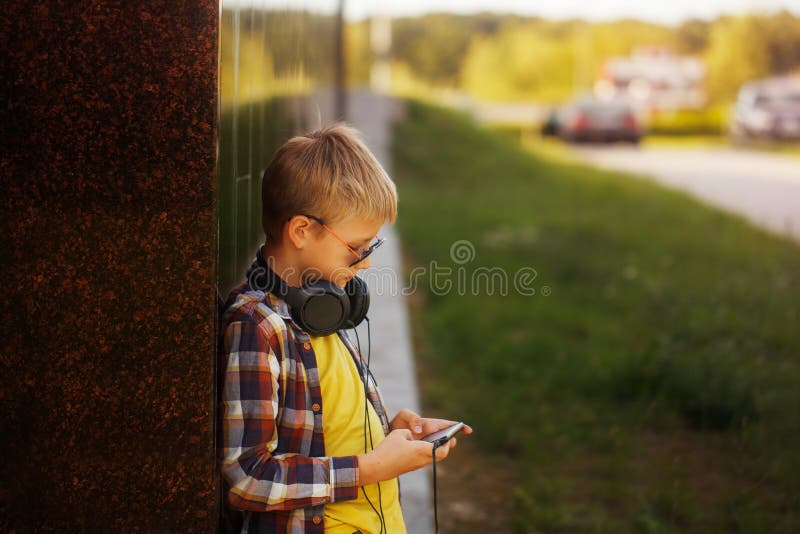 Przystojny nastoletni chłopak słucha muzyka i używa telefon obrazy royalty free Przystojny nastoletni chłopak słucha muzyka i używa telefon obrazy royalty free