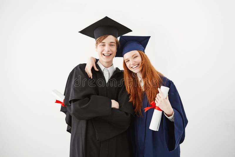 Przytłaczająca para uniwersytet kończy studia szczęśliwego otrzymywać ich dyplomy, ono uśmiecha się przy kamerą, rudzielec dziewc zdjęcie royalty free Przytłaczająca para uniwersytet kończy studia szczęśliwego otrzymywać ich dyplomy, ono uśmiecha się przy kamerą, rudzielec dziewc zdjęcie royalty free