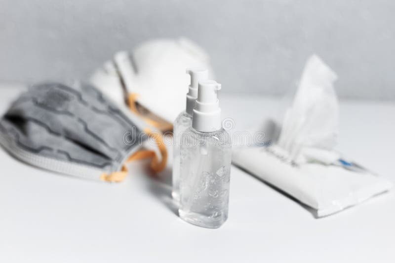 Coronavirus prevention. Two bottles of sanitizer antiseptic gel near medical flu masks and wipes wet on white table. Top view. Coronavirus prevention. Two bottles of sanitizer antiseptic gel near medical flu masks and wipes wet on white table. Top view