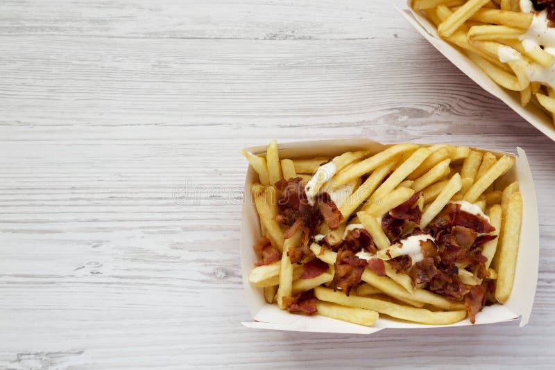 Prêt-à-manger savoureux : pommes frites avec de la sauce au fromage et le lard dans des boîtes de papier Configuration plate, d'e images libres de droits Prêt-à-manger savoureux : pommes frites avec de la sauce au fromage et le lard dans des boîtes de papier Configuration plate, d'e images libres de droits
