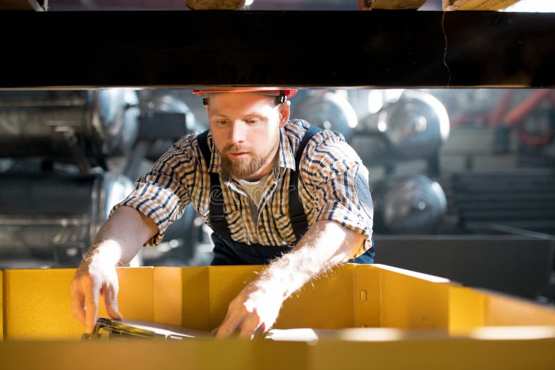 Prüfung des Mechanismus. Junger Ingenieur in der Arbeitskleidung Prinzipien der Mechanismusarbeit beim Arbeiten lernend mit technischer Ausrüstung