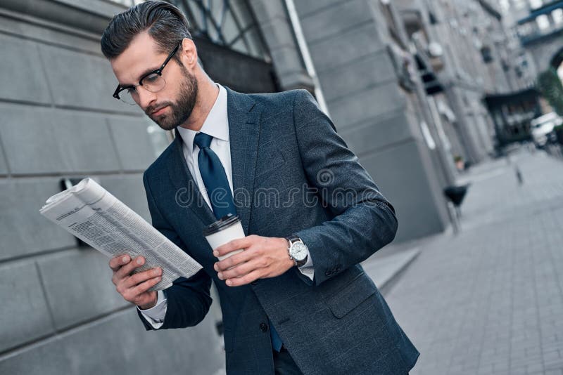 Prüfung von Wirtschaftsnachrichten Schöner junger Mann in der vollen Klage las lizenzfreies stockfoto Prüfung von Wirtschaftsnachrichten Schöner junger Mann in der vollen Klage las lizenzfreies stockfoto