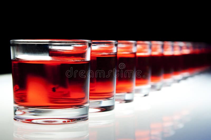 Several red alcohol shots on a bar. Several red alcohol shots on a bar.