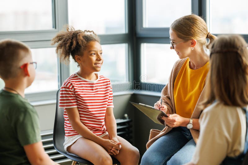 Psicologo scolastico con un gruppo di bambini conduce una lezione di salute mentale terapia una sessione di psicoterapia fotografia stock
