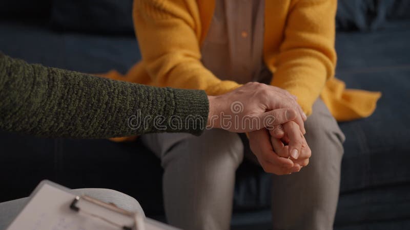 Psicóloga sentada y mano táctil joven deprimida para animar en un sofá con un ambiente de baja luz ptsd metrajes