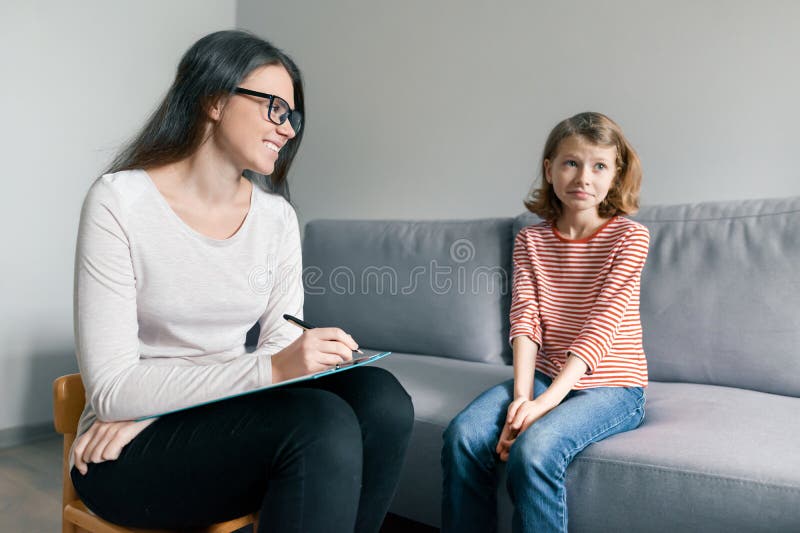 Psicólogo fêmea novo que fala com a menina paciente da criança no escritório Saúde mental das crianças fotografia de stock royalty free Psicólogo fêmea novo que fala com a menina paciente da criança no escritório Saúde mental das crianças fotografia de stock royalty free