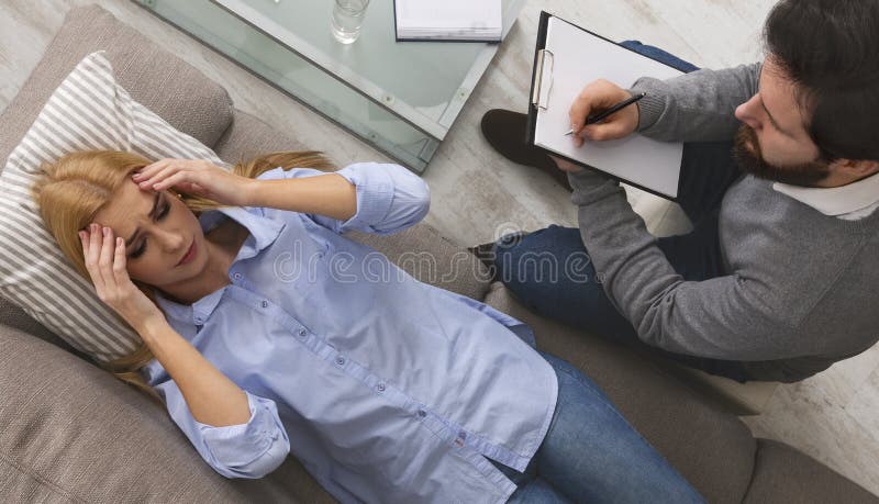 Psicólogo que escuta o paciente desesperado e que escreve para baixo notas imagens de stock Psicólogo que escuta o paciente desesperado e que escreve para baixo notas imagens de stock