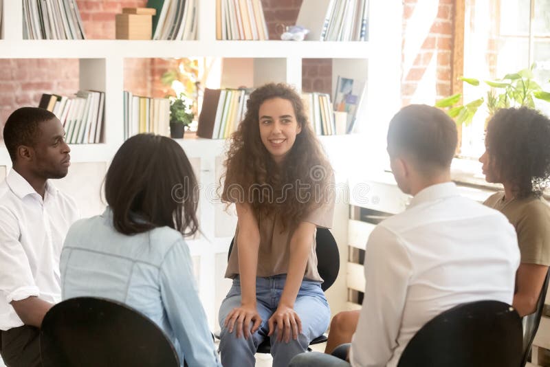 Psychologe der jungen Frau, der im Kreis unter der verschiedenen Leuteunterhaltung sitzt