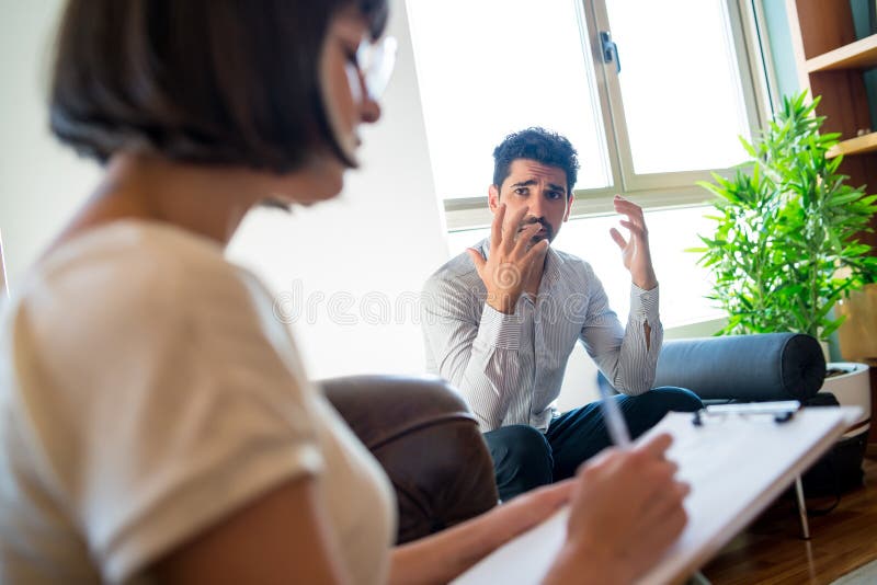psychologist-taking-notes-during-therapy-session-stock-photo-image