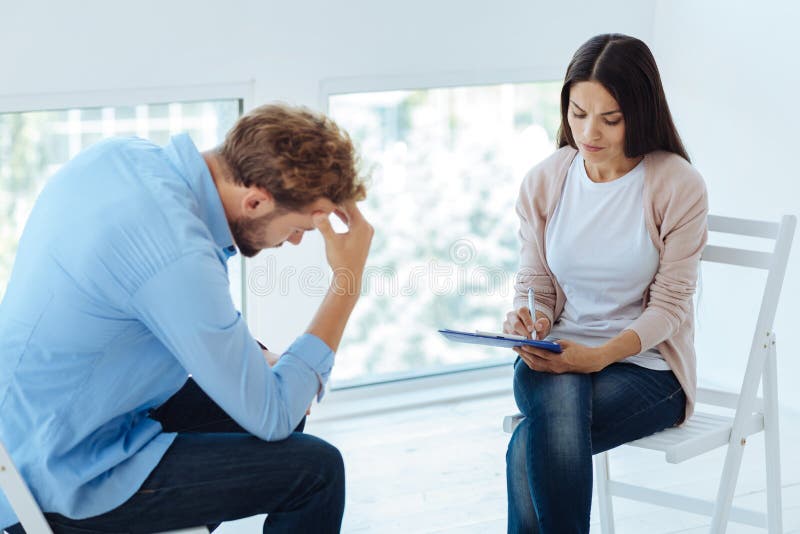 Professional Experienced Therapist Noting Down the Symptoms Stock Photo