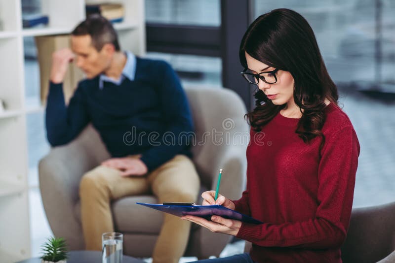 Psychologue faisant des notes dans le document image libre de droits Psychologue faisant des notes dans le document image libre de droits