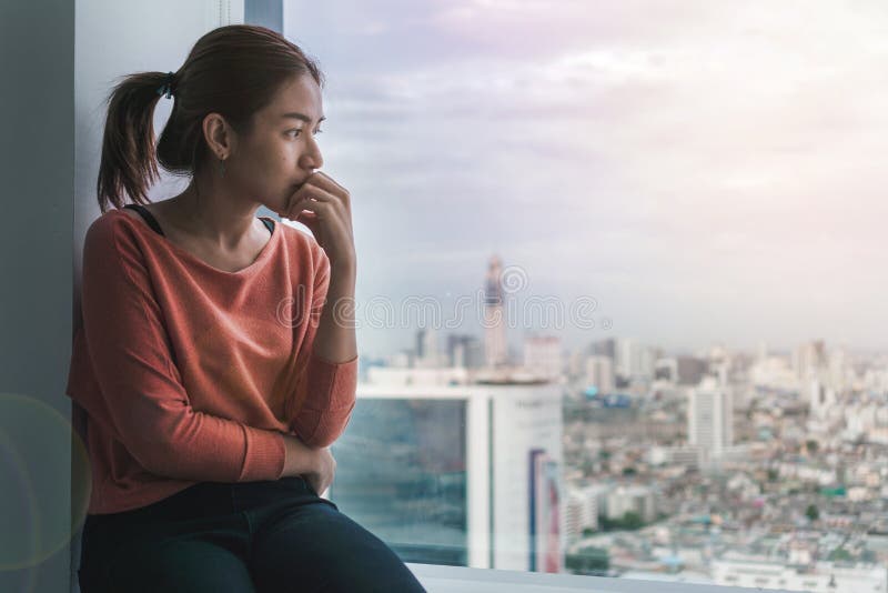 PTSD Mental health concept, Young depressed asian woman sitting near window with low light environment.Selective focus. royalty free stock images