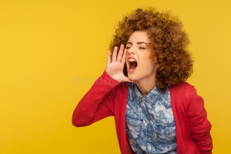 Publicité d'attention! Portrait de la femme aux cheveux bouclés hurlant formées dans des mains comme le mégaphone photos libres de droits