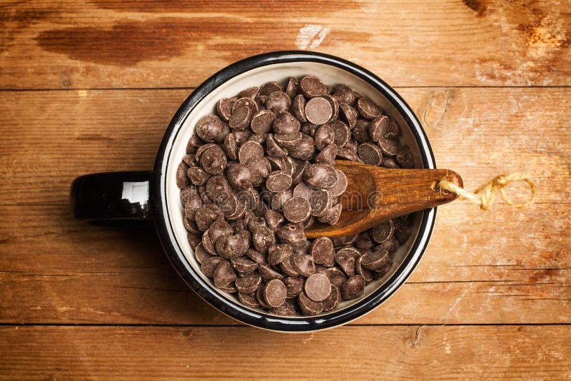 Puces de chocolat dans une tasse avec une cuillère en bois image stock Puces de chocolat dans une tasse avec une cuillère en bois image stock