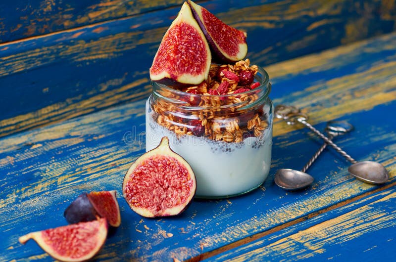 Pudding de lait de Chia avec la granola et les figues coupées en tranches fraîches dans le pot en verre décoré des cuillères de v photos stock Pudding de lait de Chia avec la granola et les figues coupées en tranches fraîches dans le pot en verre décoré des cuillères de v photos stock