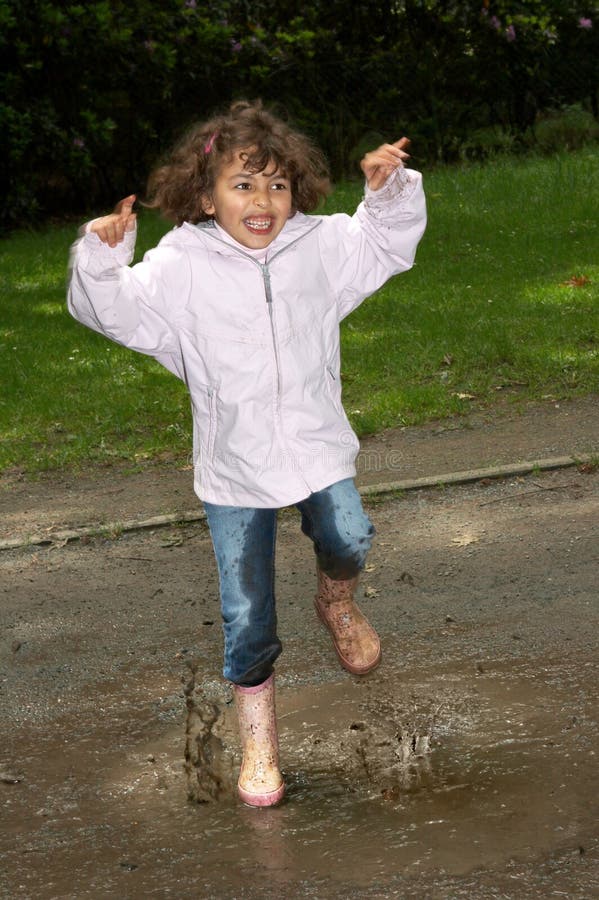 Little girl dancing in the park, splashing in a water puddle. Little girl dancing in the park, splashing in a water puddle