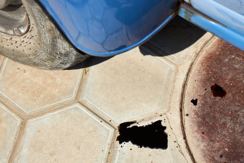 A Puddle of Oil Due To a Leak from Under an Old Car Stock Photo Image