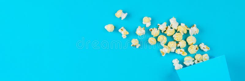 Pudełko rozlewający na błękitnym tle popkorn obraz royalty free Pudełko rozlewający na błękitnym tle popkorn obraz royalty free