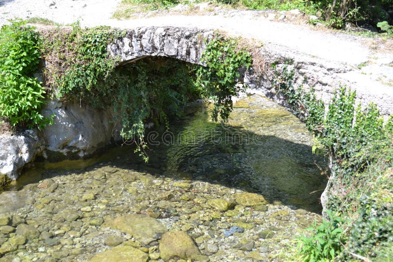 Puente antiguo de la piedra del arco sobre la corriente de la montaña imagenes de archivo Puente antiguo de la piedra del arco sobre la corriente de la montaña imagenes de archivo