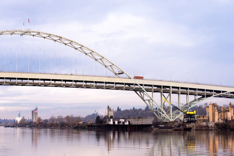 Spectacular original unique arched Fremont bridge across the Willamette River in the city bridges Portland Oregon in a quiet calm weather with reflection in water and cloudy sky. Spectacular original unique arched Fremont bridge across the Willamette River in the city bridges Portland Oregon in a quiet calm weather with reflection in water and cloudy sky.