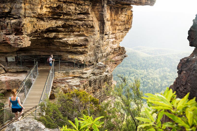Puente a las hermanas de la formación de roca tres con los caminantes que miran en el valle, Katoomba, Nuevo Gales del Sur, Austr imagenes de archivo Puente a las hermanas de la formación de roca tres con los caminantes que miran en el valle, Katoomba, Nuevo Gales del Sur, Austr imagenes de archivo
