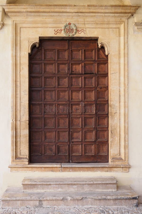 Puerta de madera adornada vieja de una iglesia medieval italiana en Spello imagen de archivo Puerta de madera adornada vieja de una iglesia medieval italiana en Spello imagen de archivo