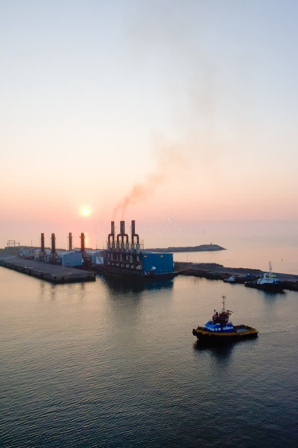 Scenic view of sunset over Puerto Quetzal port, Guatemala. Tug boat in foreground. Scenic view of sunset over Puerto Quetzal port, Guatemala. Tug boat in foreground.