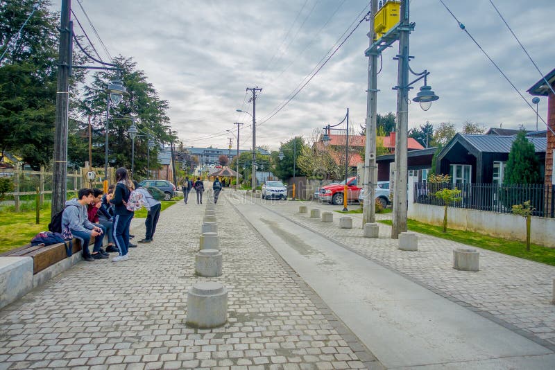 PUERTO VARAS, CHILE, SEPTEMBER, 23, 2018: Outdoor view of group of highschool students sitting at one side of a sidewalk stock photo