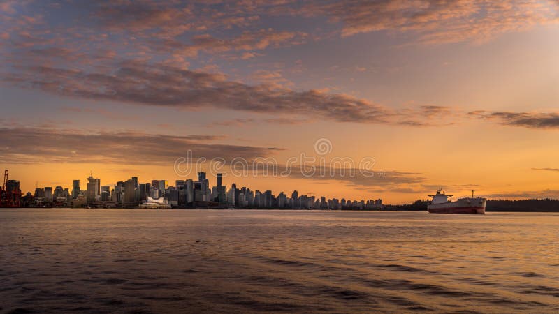Puesta de sol sobre el horizonte del centro de vancouver con un carguero oceánico amarrado en el puerto fotos de archivo
