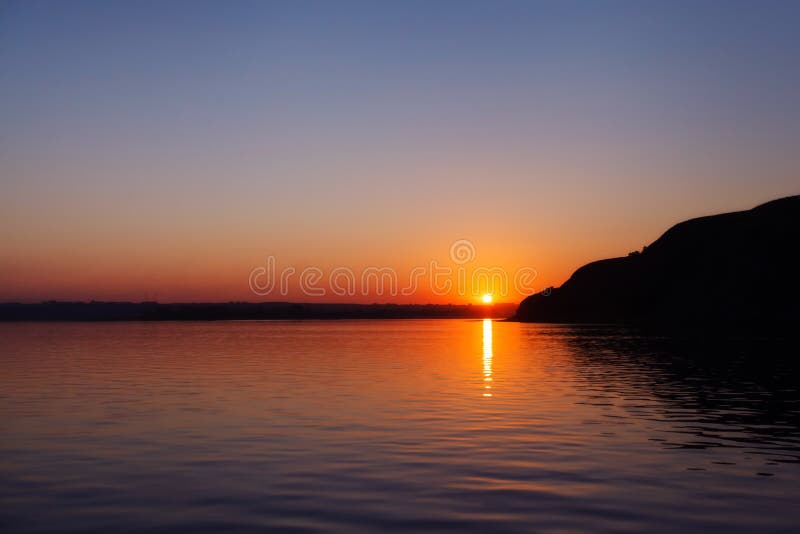 Puesta del sol anaranjada hermosa sobre el río con reflejo foto de archivo Puesta del sol anaranjada hermosa sobre el río con reflejo foto de archivo