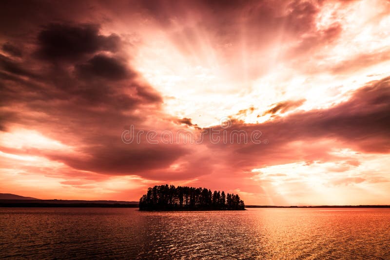 Puesta del sol anaranjada roja sobre el lago con una pequeña isla fotografía de archivo libre de regalías Puesta del sol anaranjada roja sobre el lago con una pequeña isla fotografía de archivo libre de regalías