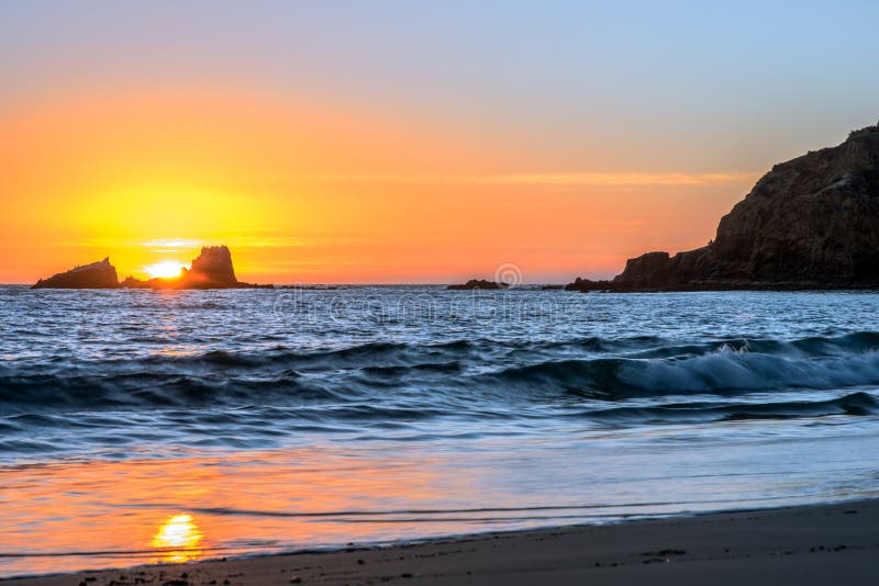 Sun setting between two rocks at crescent bay in Laguna Beach, CA. Sun setting between two rocks at crescent bay in Laguna Beach, CA