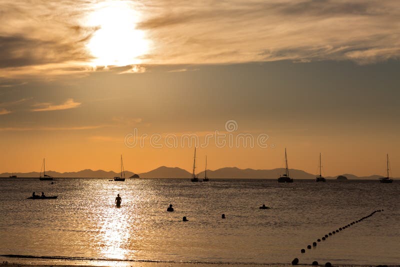 Puesta del sol de oro hermosa con la trayectoria del sol y las siluetas de la gente en el agua que admira la puesta del sol Silue foto de archivo libre de regalías Puesta del sol de oro hermosa con la trayectoria del sol y las siluetas de la gente en el agua que admira la puesta del sol Silue foto de archivo libre de regalías