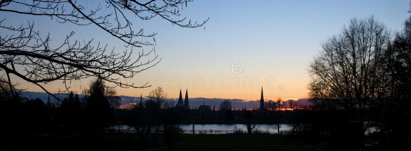 Puesta del sol detrás de las torres de iglesia de Luebeck, Alemania septentrional foto de archivo libre de regalías Puesta del sol detrás de las torres de iglesia de Luebeck, Alemania septentrional foto de archivo libre de regalías