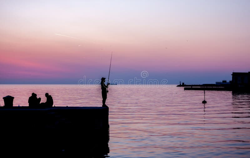 Puesta del sol en pescador del puerto de Trieste en el embarcadero imagenes de archivo Puesta del sol en pescador del puerto de Trieste en el embarcadero imagenes de archivo