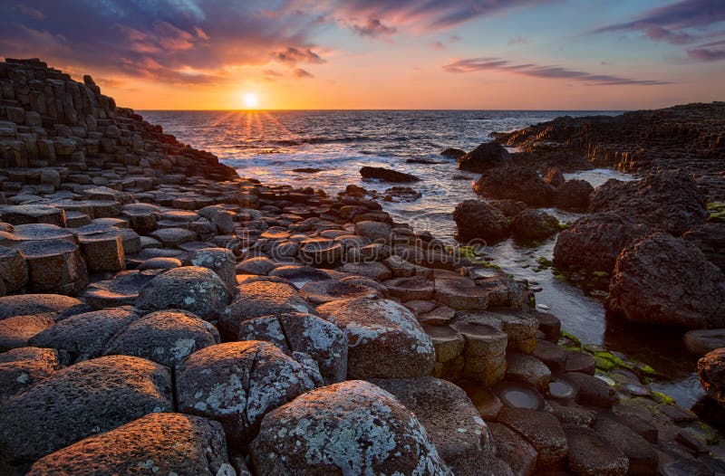 Puesta del sol sobre el terraplén gigante del ` s de las columnas del basalto, condado Antrim, Irlanda del Norte fotos de archivo Puesta del sol sobre el terraplén gigante del ` s de las columnas del basalto, condado Antrim, Irlanda del Norte fotos de archivo
