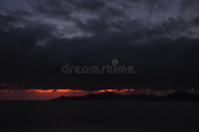 Dark suggestive sunset of the island of Praslin from La Digue Island, Seychelles. Dark suggestive sunset of the island of Praslin from La Digue Island, Seychelles