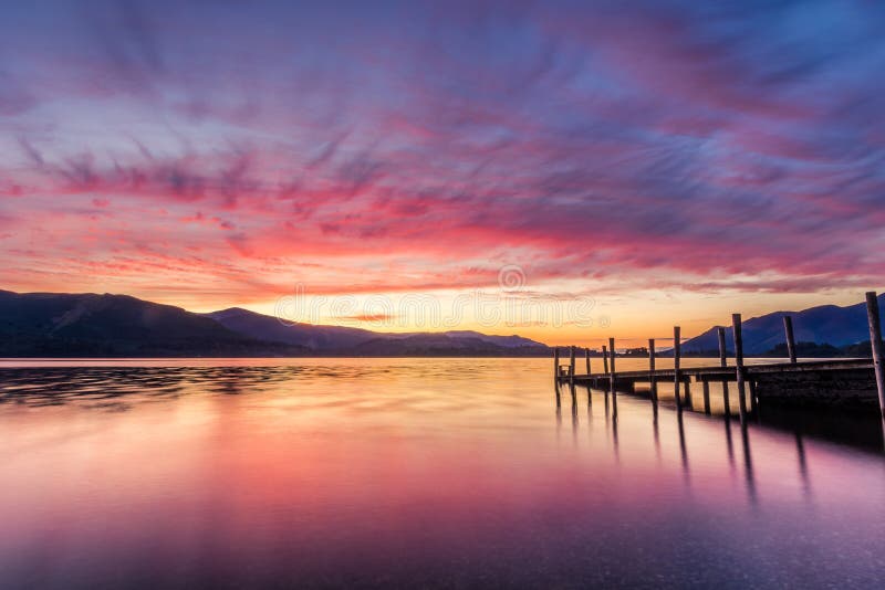 Puesta del sol vibrante imponente en el embarcadero de Ashness en Keswick, el distrito del lago, Reino Unido fotografía de archivo Puesta del sol vibrante imponente en el embarcadero de Ashness en Keswick, el distrito del lago, Reino Unido fotografía de archivo