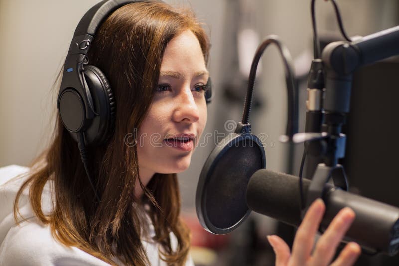 Puleggia tenditrice femminile Talking On Microphone in studio radiofonico fotografia stock Puleggia tenditrice femminile Talking On Microphone in studio radiofonico fotografia stock