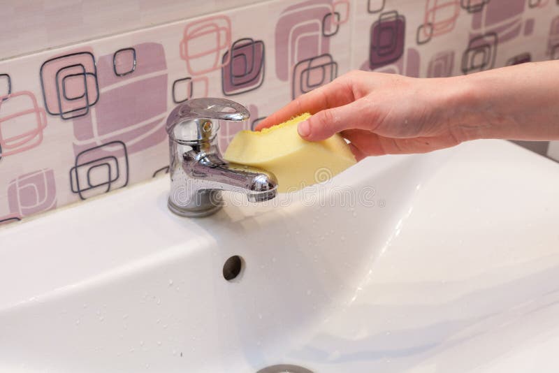 Pulendo un nuovo bagno del metallo spilli con la spugna gialla immagine stock Pulendo un nuovo bagno del metallo spilli con la spugna gialla immagine stock