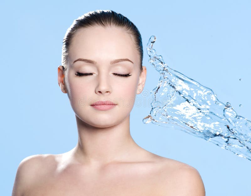Clean skin on the face of young beautiful young woman and stream of water - blue background. Clean skin on the face of young beautiful young woman and stream of water - blue background